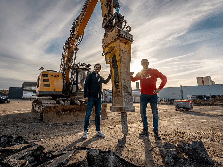 Ground-breaking ceremony - Marc and Jochen Böck in front of a demolition excavator on the future company site