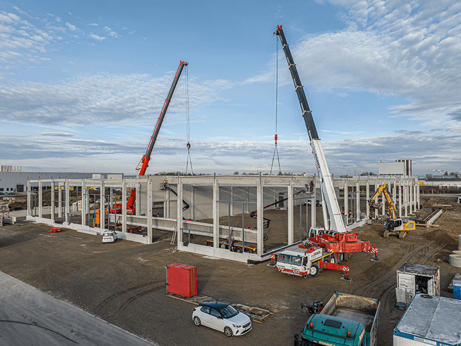 Heavy concrete cross beams 33 meters long are brought into position with heavy equipment.